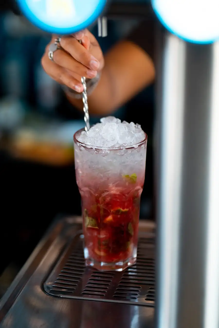 Main d’un barman en train de mélanger un cocktail derrière le comptoir
