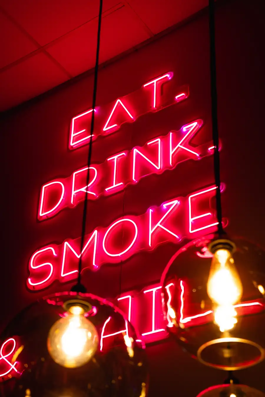 Néon rose « Eat. Drink. Smoke & Chill » et ampoules suspendues